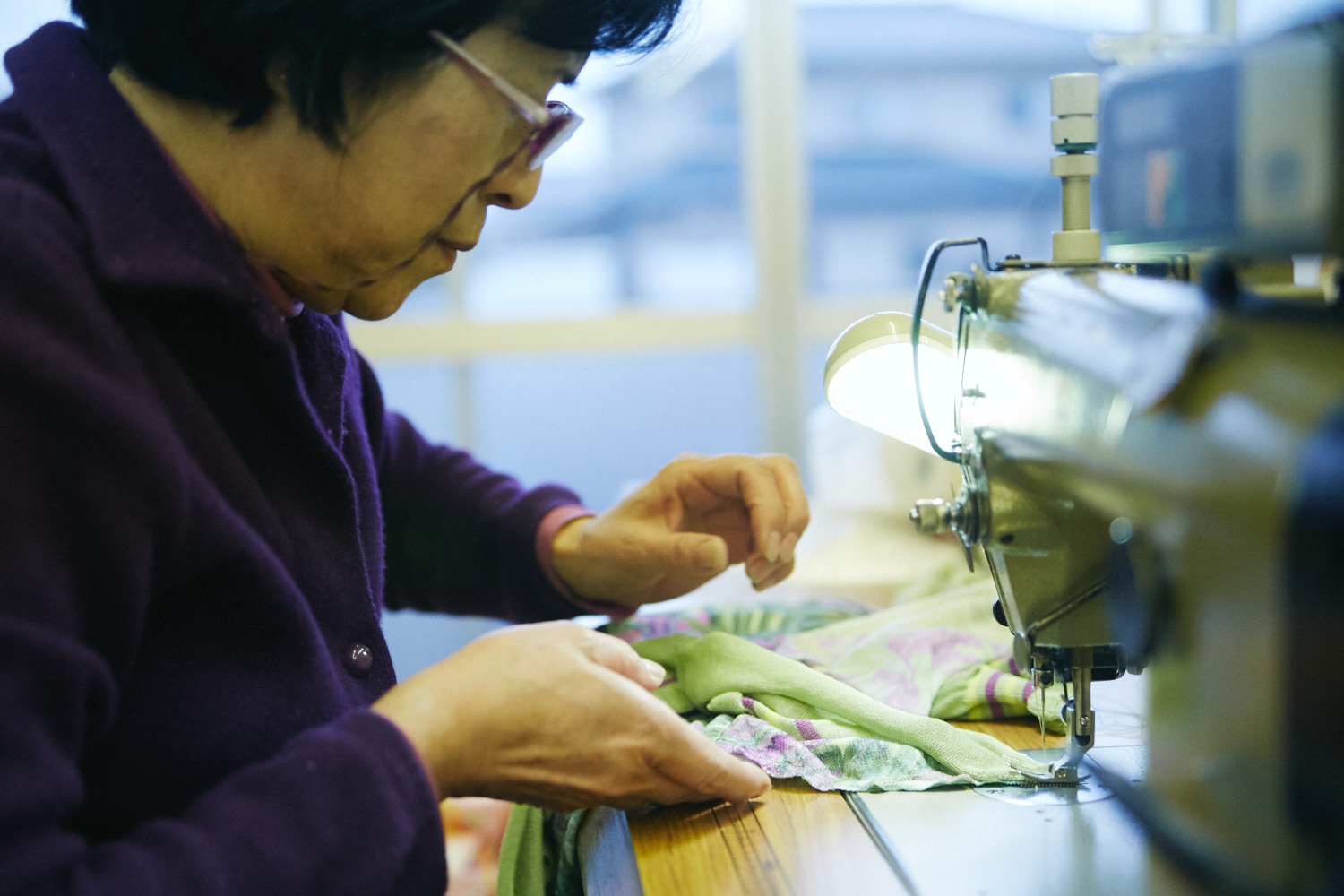 サンプルの縫製を担う職人の女性。「ベテランなので、量産よりも早くできちゃうんです。試作を彼女に縫ってもらって、工賃を計算するんですけど、彼女が早過ぎるので工賃が足りなくなる、なんてことも……(笑)」〈啓司さん〉