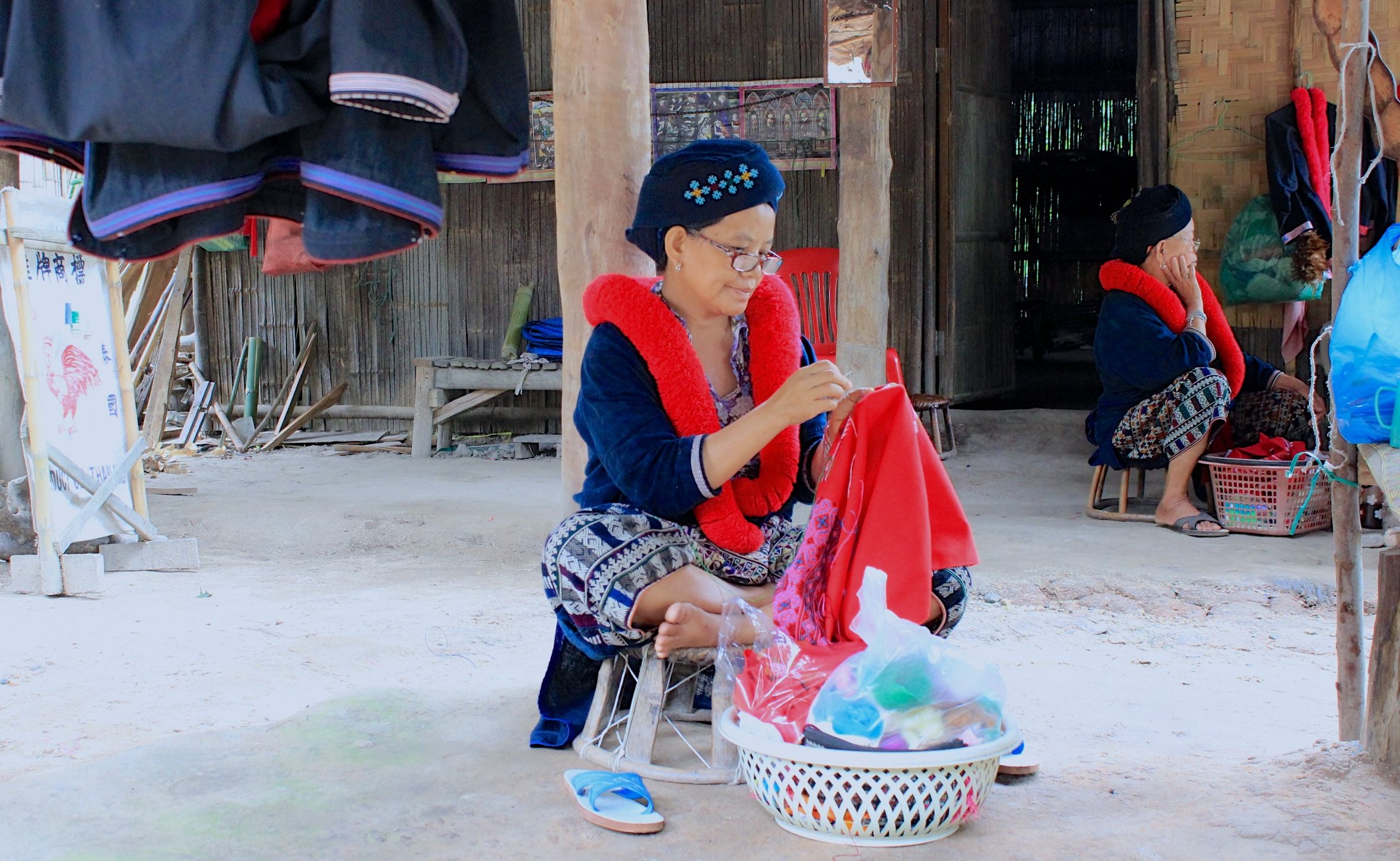 赤い毛糸で作られた、ミェン族を象徴する装飾を纏って縫製作業をする女性。（提供：FUJI TATE P）